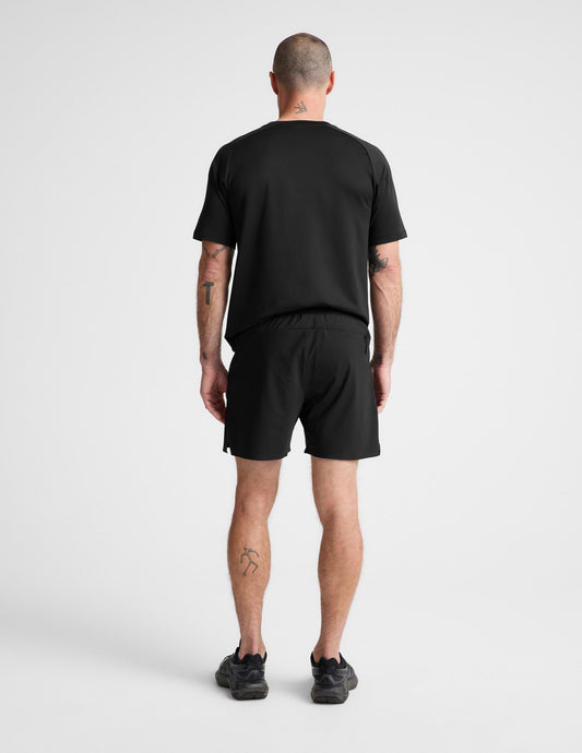 Man wearing Black WarpLite™ Range Lined Short paired with a black t-shirt and sneakers, Rear view.