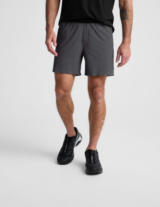 Man wearing Gray WarpLite™ Range Lined Short with a 6-inch inseam, paired with a black t-shirt and black sneakers.