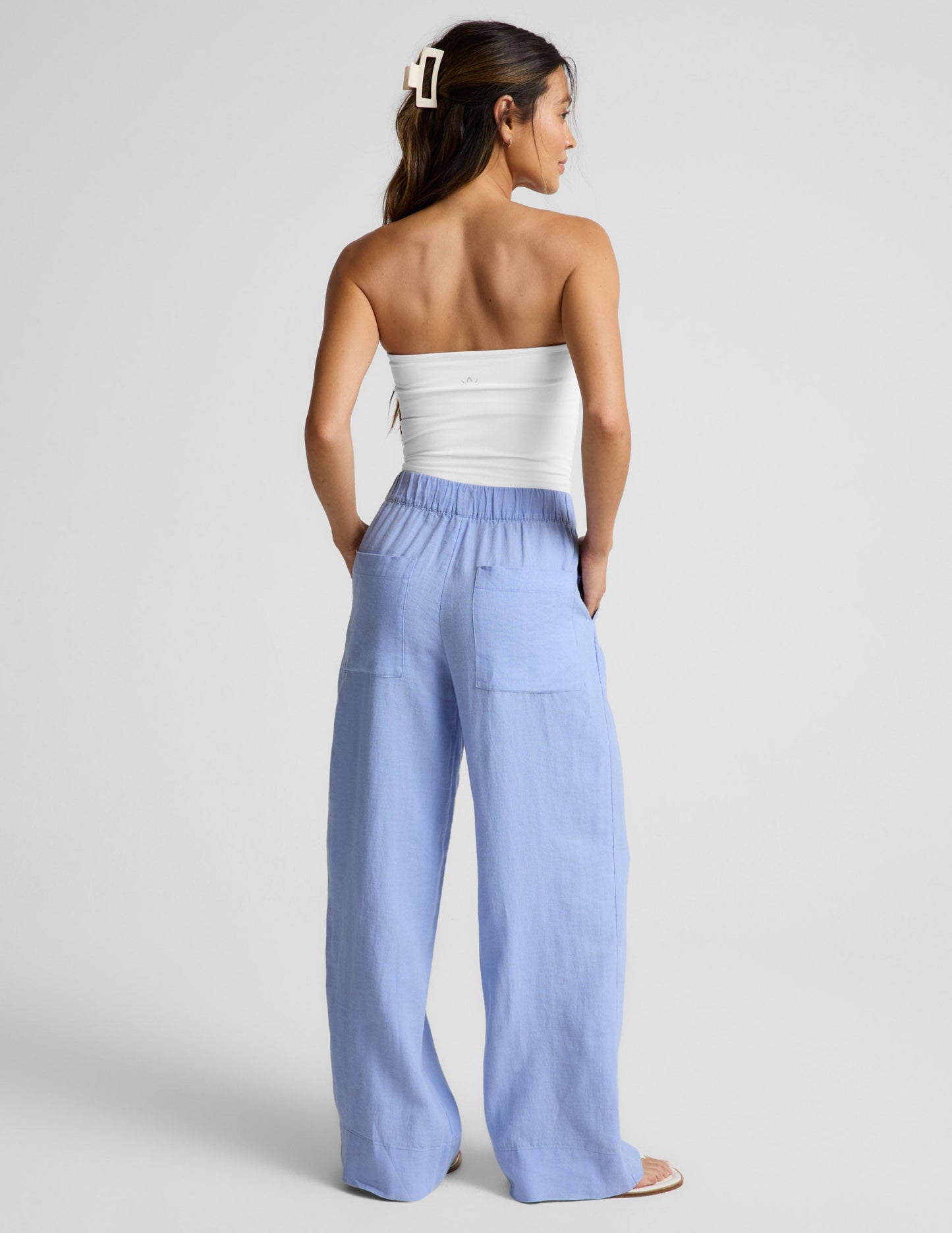 Woman wearing Blue SoftWash Linen Easy Wide Leg Pant 31" paired with a white strapless top, Rear view.