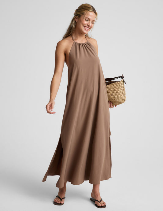Woman wearing a brown halter maxi dress against a plain background.