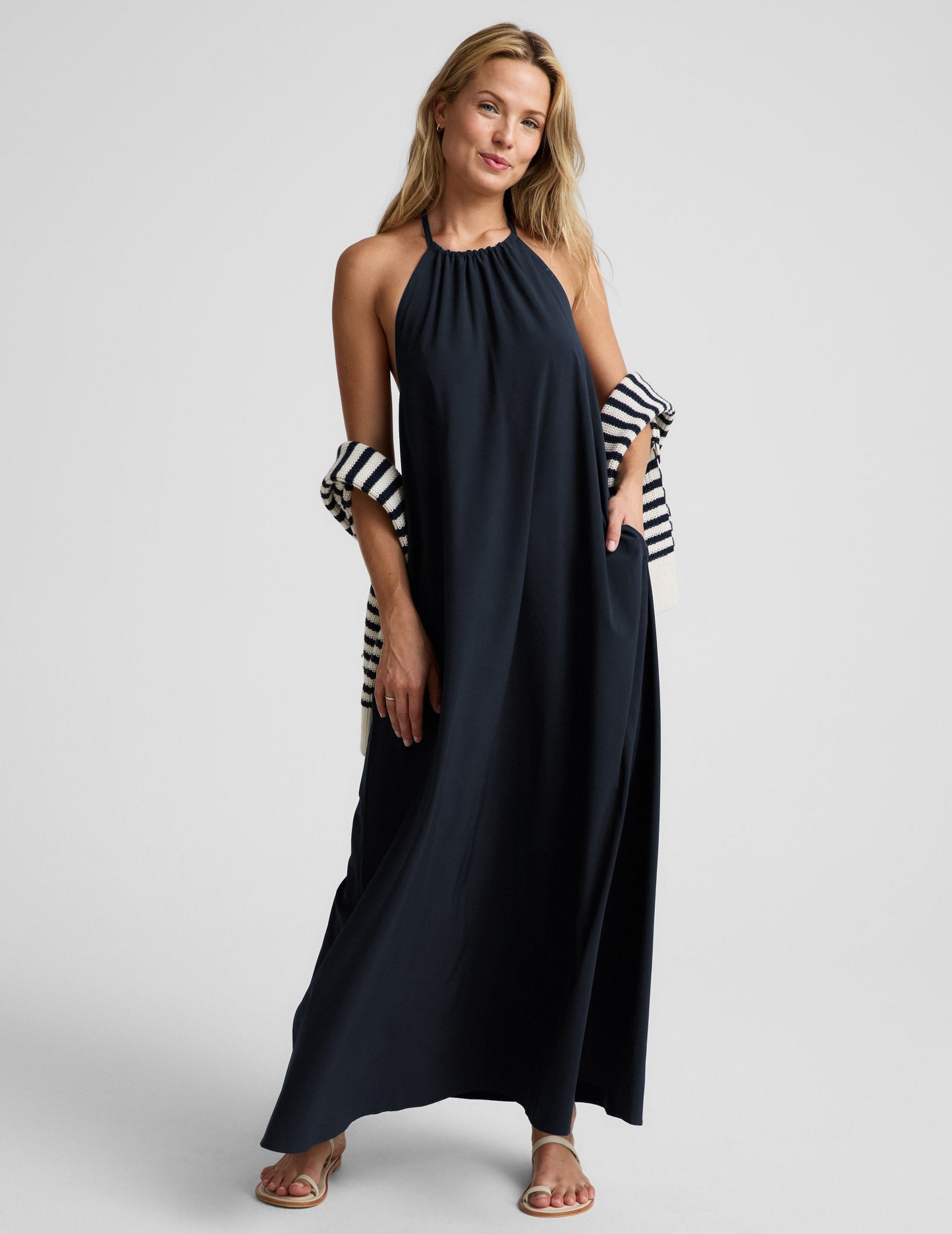 Woman wearing a navy blue halter maxi dress against a plain background.