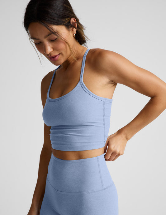 Woman wearing a blue cropped racerback tank and leggings against a plain background.