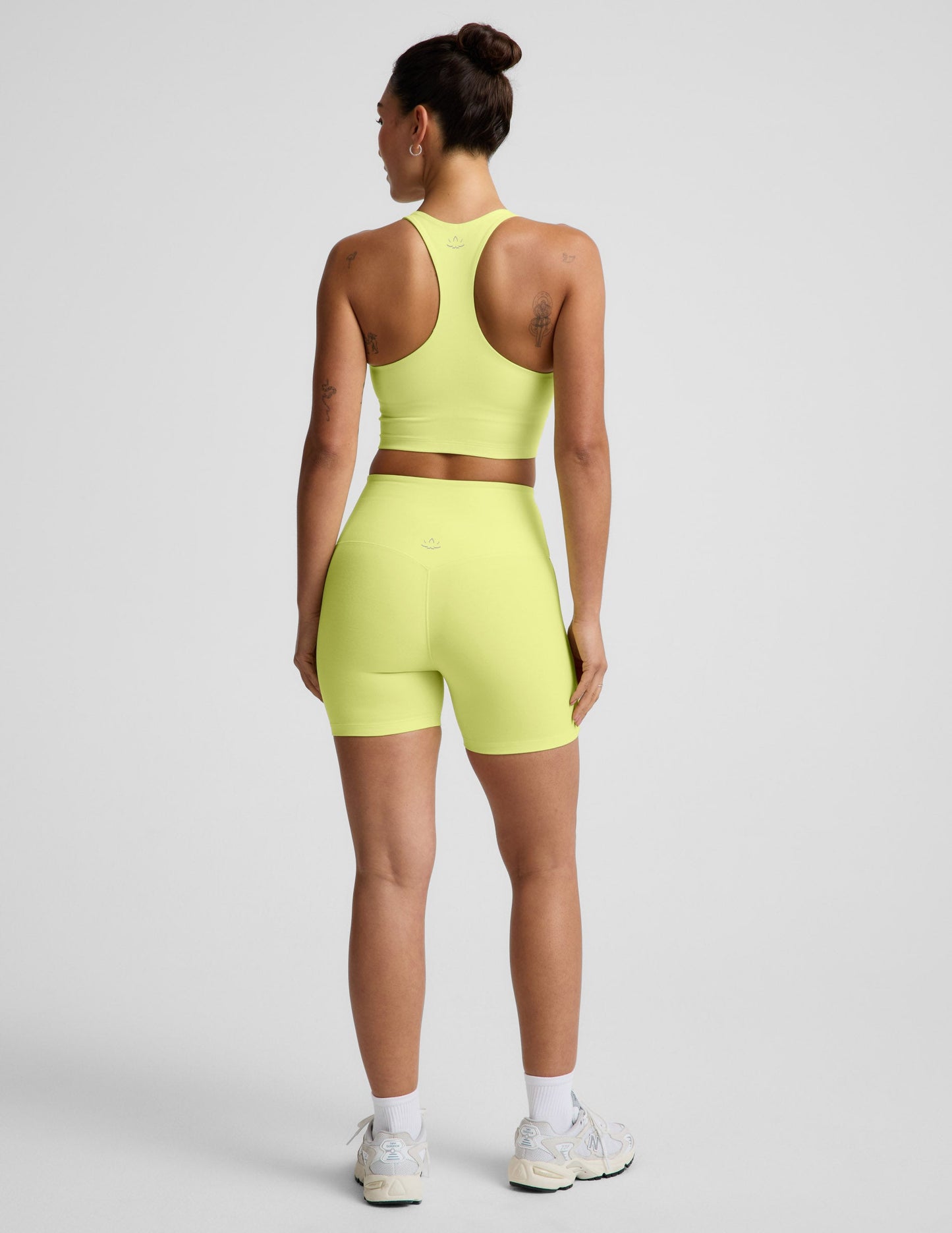 Woman wearing Yellow Spacedye™ Streamline 5" Short, paired with a matching tank and sneakers. Rear view.