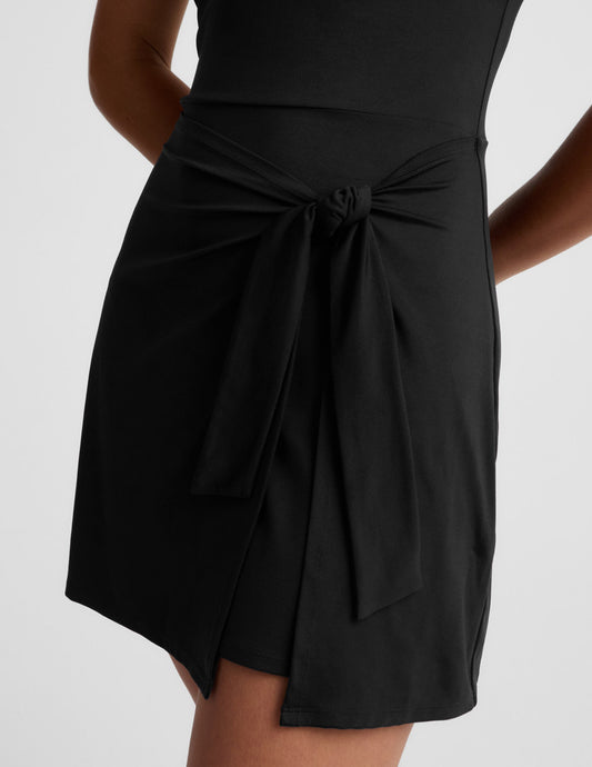 Woman wearing a black mini sleeveless dress on a white background.
