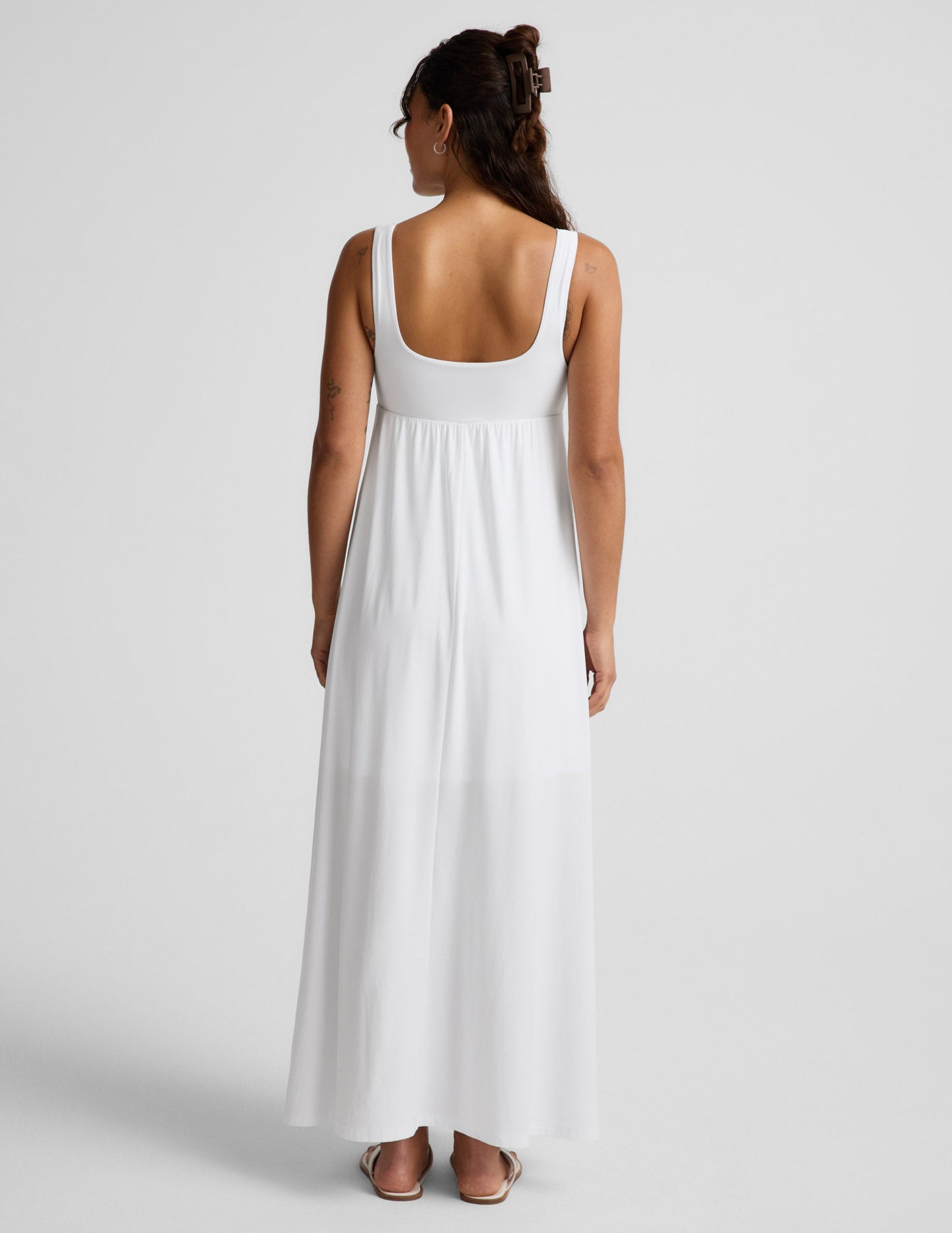 Woman wearing a white sleeveless dress on a plain background.
