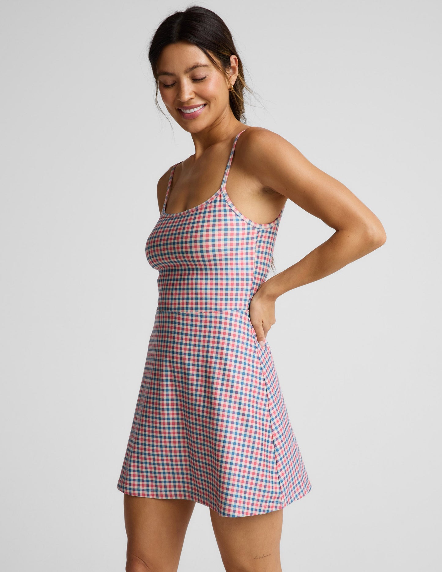 Woman wearing a gingham dress against a light gray background.