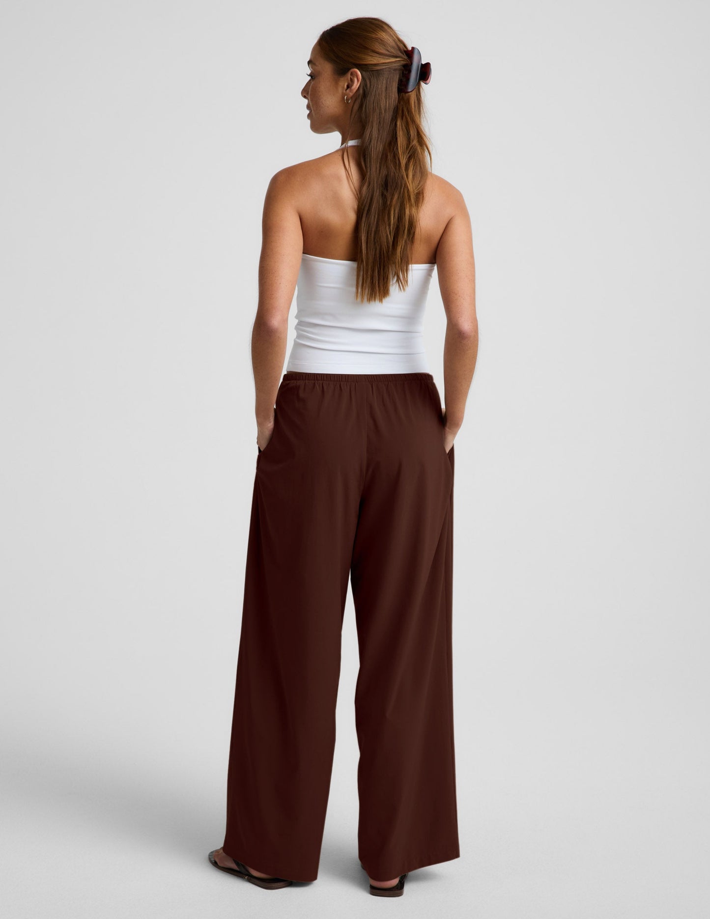 Woman wearing Brown Solstice™ Drawstring Wide Leg Pant 29" with a white tube top, Rear view.