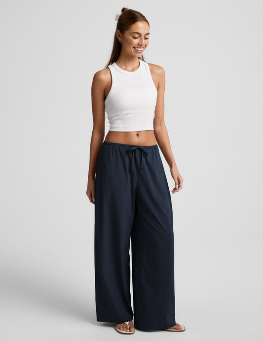 Woman wearing Navy Solstice™ Drawstring Wide Leg Pant 29" paired with a white ribbed cropped tank top.
