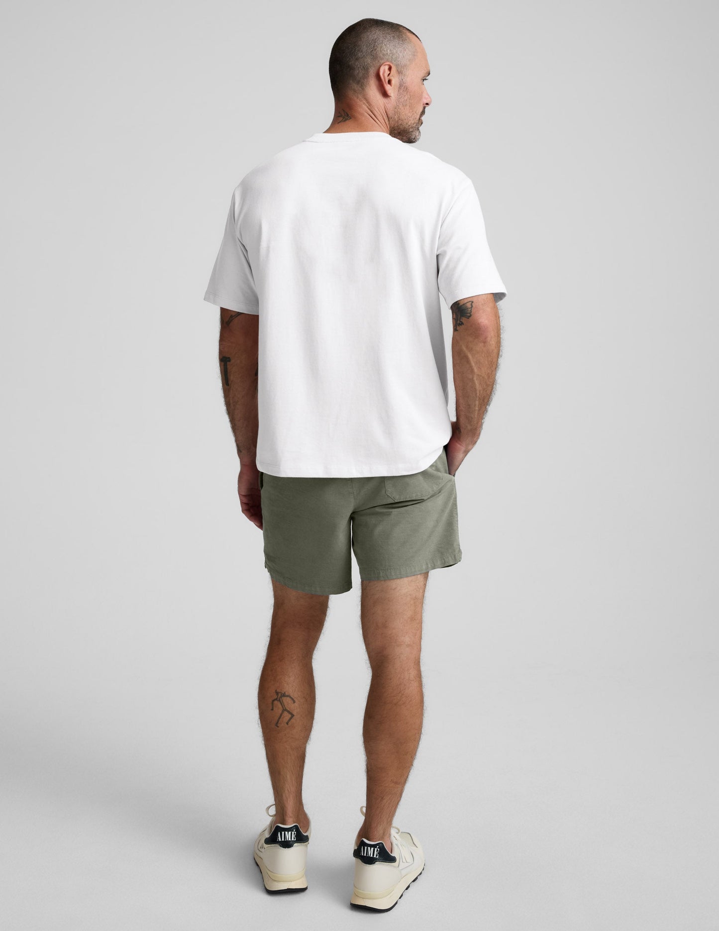 Rear view of olive green Saturday Men's Short featuring a back patch pocket and comfortable mid-thigh fit on a model.
