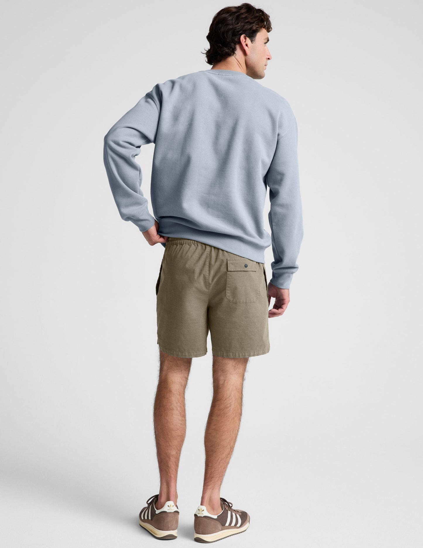 Rear view of the olive Saturday Men's Short showing the elasticated waistband and back patch pocket with a snap button.