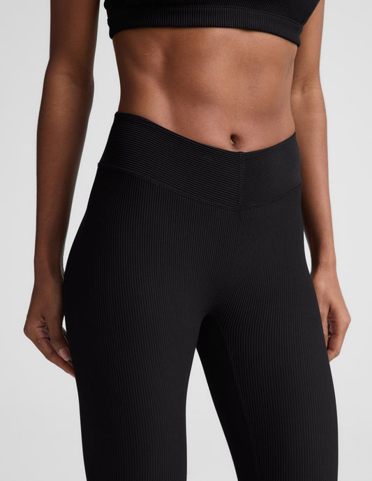 Woman wearing Black Impulse Ribbed V-Waist Pedal Pusher Legging™ paired with a matching ribbed sports bra.