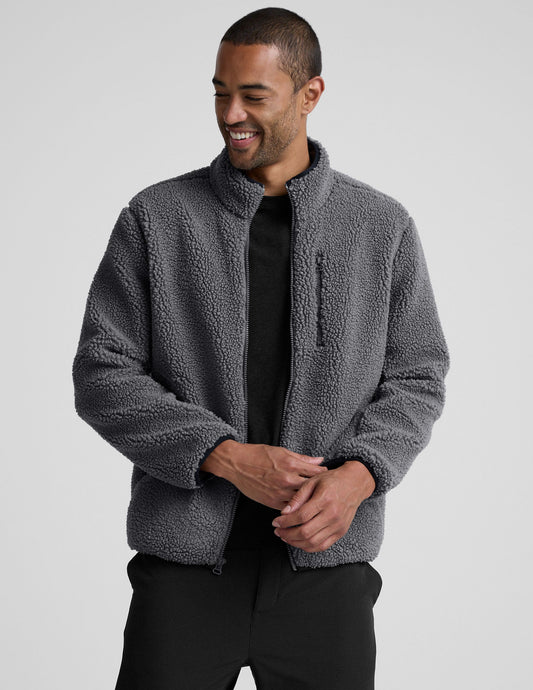 man wearing a gray fleece zip-up jacket against a plain background.
