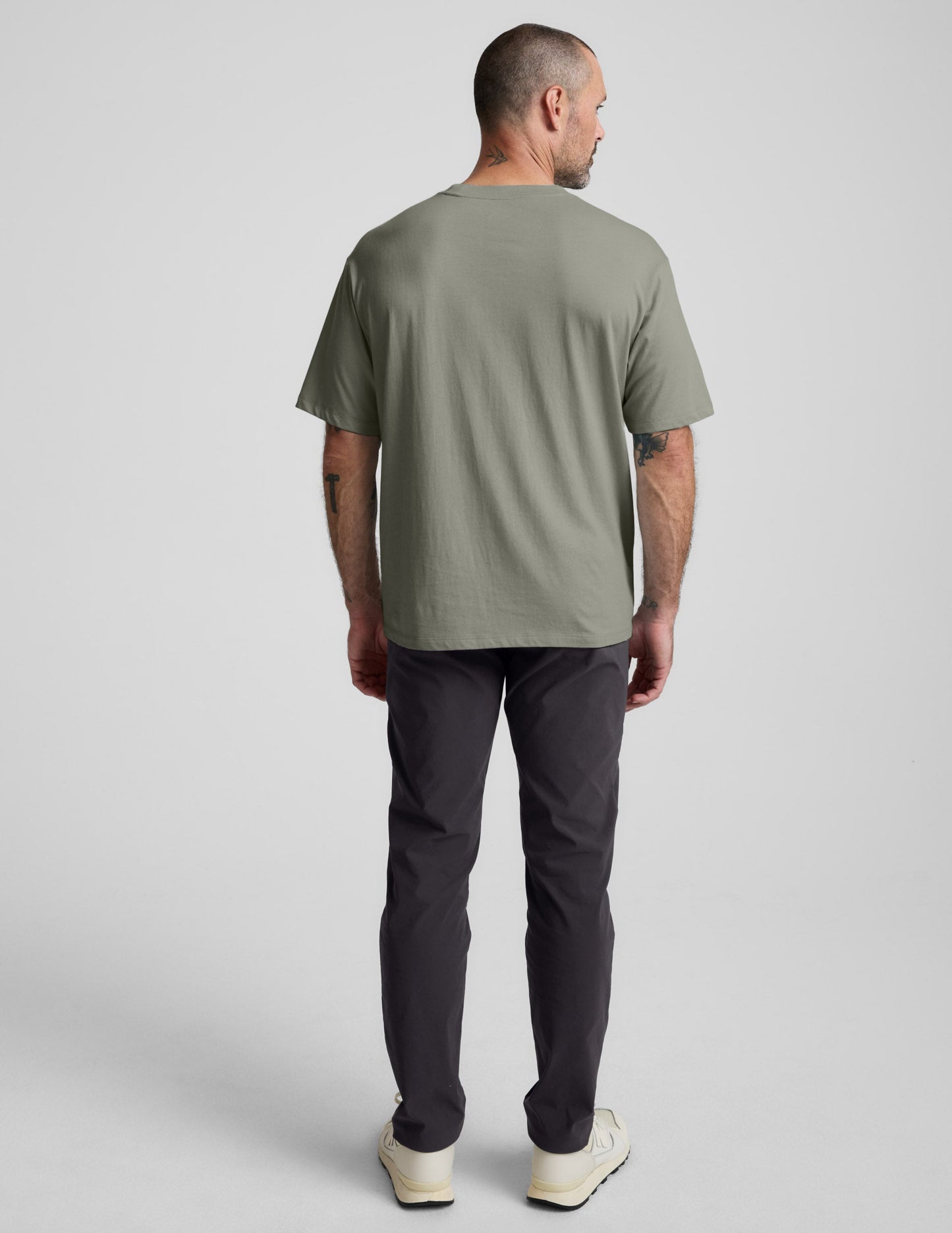 Man wearing a green cotton t-shirt and black pants against a plain background.