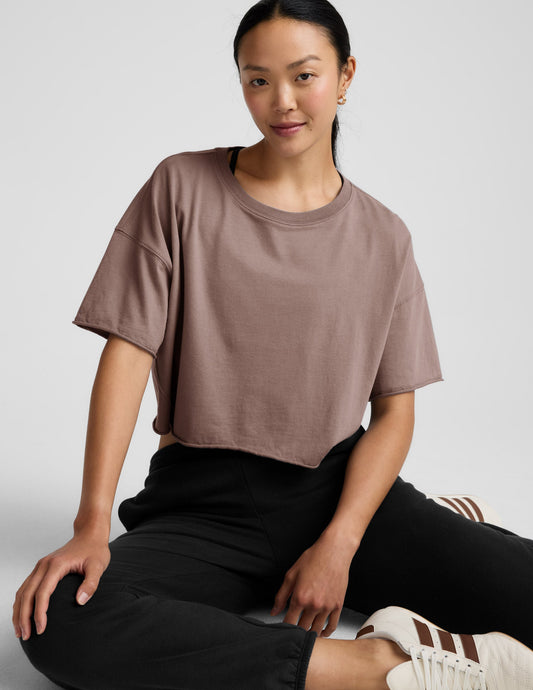 Woman wearing a brown cropped top and black pants on a light gray background.