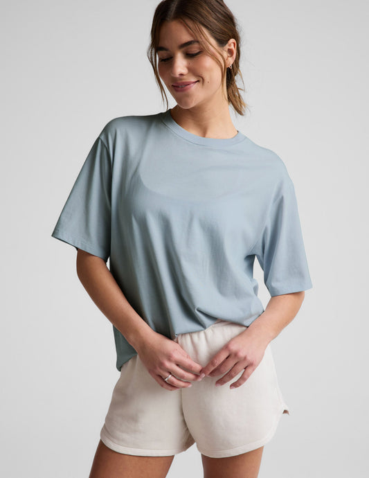 Woman wearing a blue t-shirt and white shorts against a plain background.
