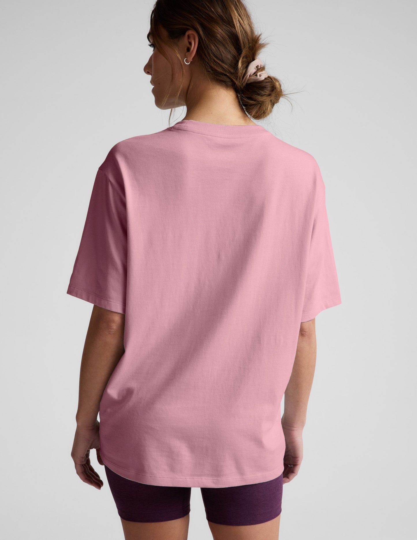 Woman wearing a pink t-shirt and purple shorts against a plain background.