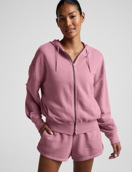 Woman wearing a pink zip-up hoodie and shorts set on a neutral background.