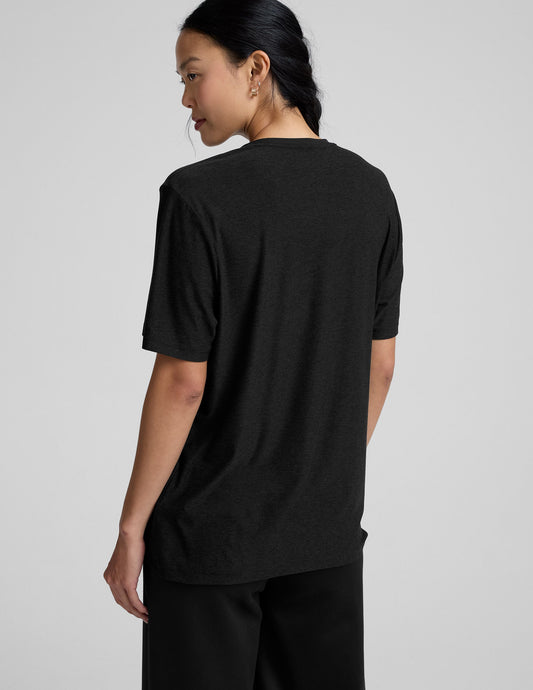 Person wearing a black t-shirt and black pants on a gray background.
