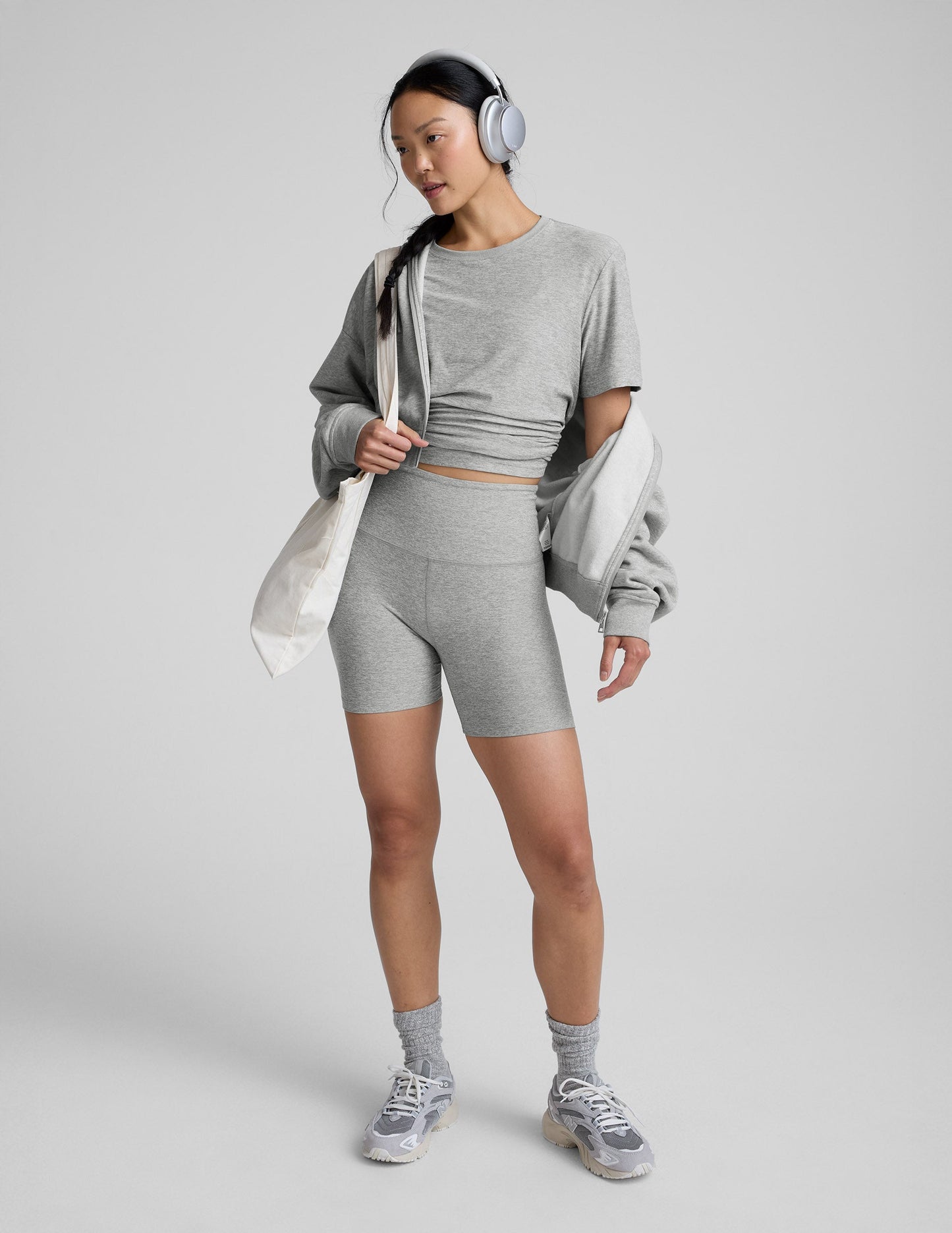 Woman wearing a gray athletic outfit on a plain background.