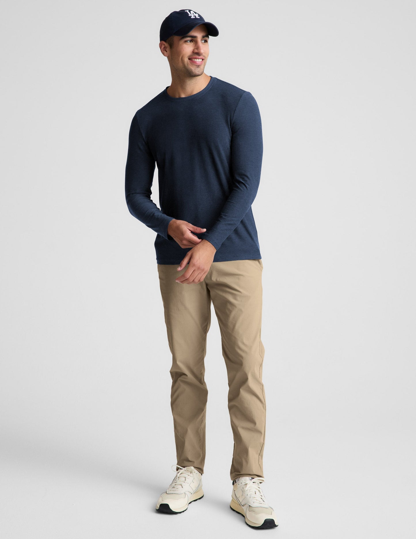 Man wearing a navy long sleeve shirt and khaki pants against a plain background.