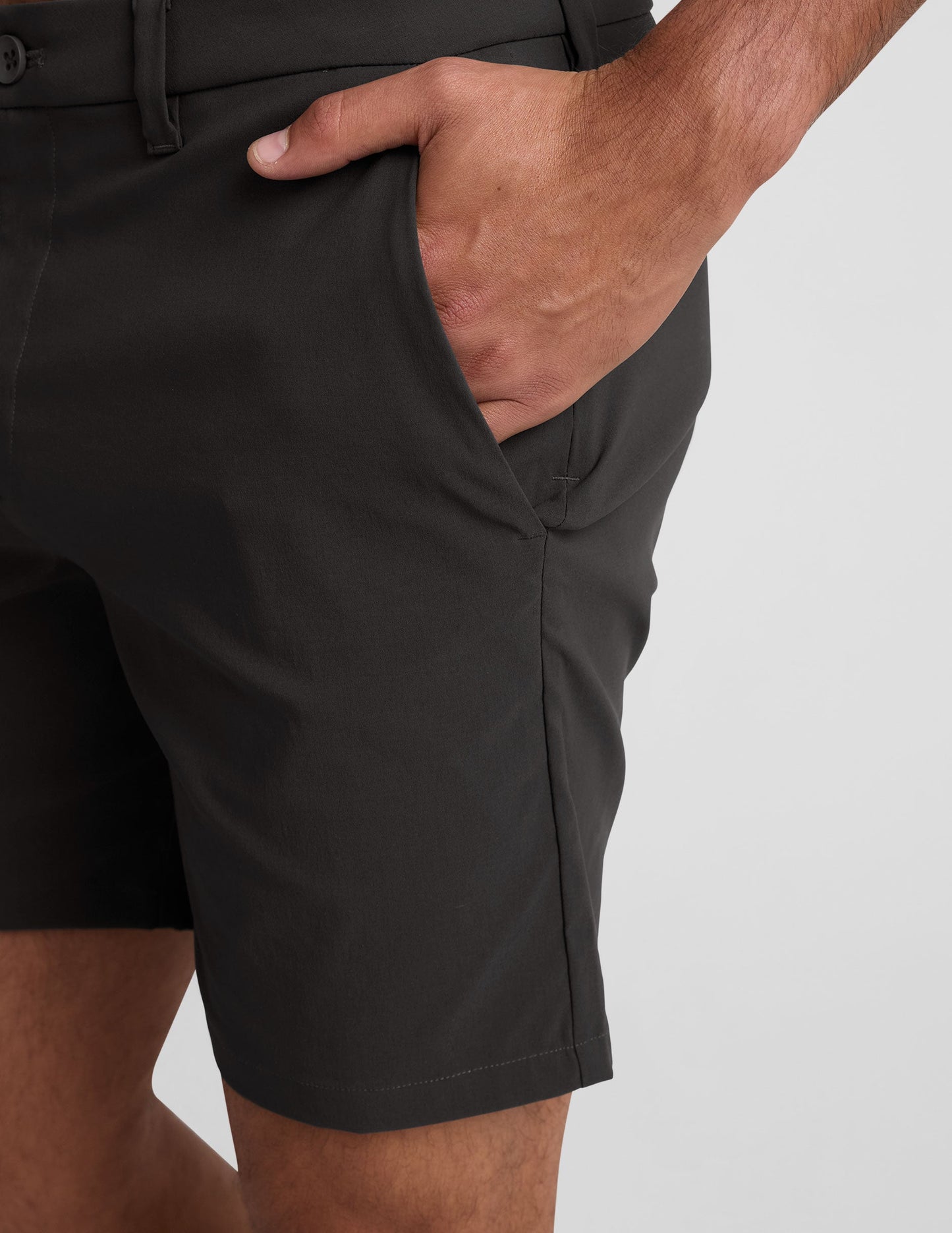 Side view of black Essential Men's Chino 7" Short showing the side pocket, belt loops, and button closure.
