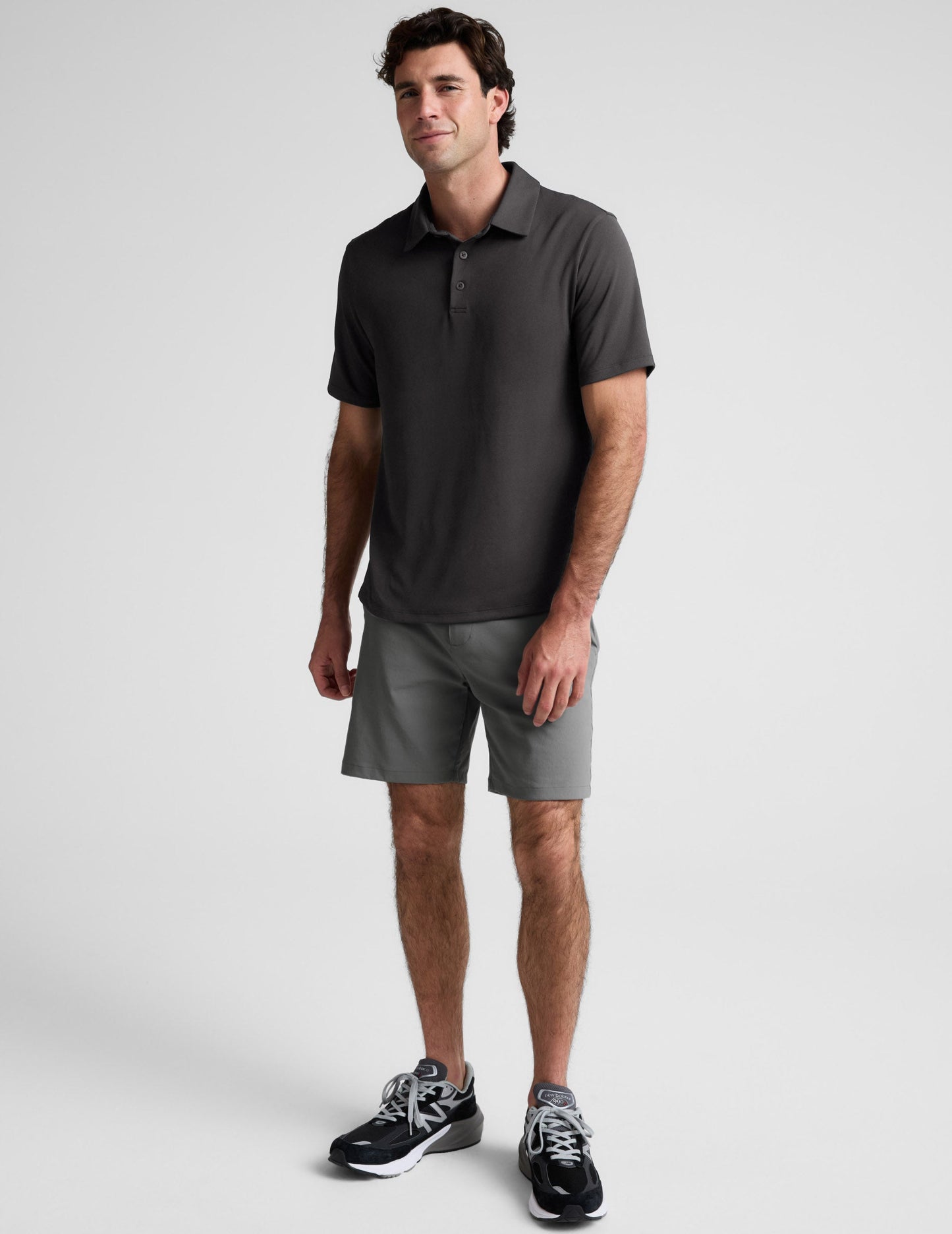 Man wearing a dark gray polo shirt against a light gray background.