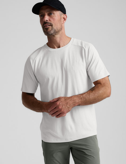 Man wearing a white t-shirt and black cap on a light gray background.