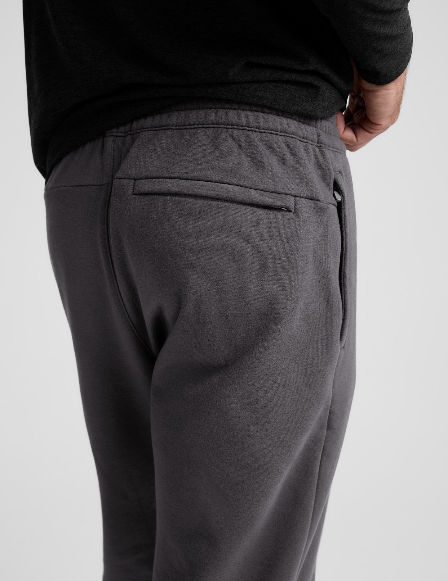 Back view of gray Classic Fleece Men's Joggers showing a rear welt pocket, side zipper, and elastic waistband.