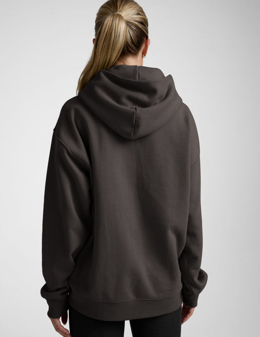 Woman wearing a dark brown hoodie on a light gray background
