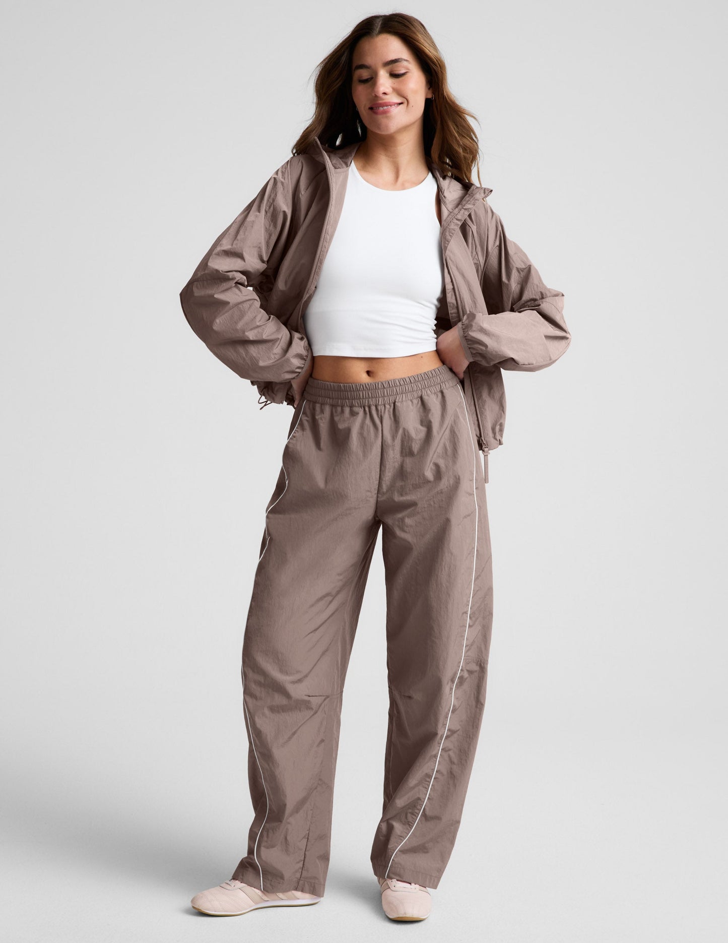 Limitless Mid-Rise Barrel Leg Pant in brown with white piping and elastic waistband on a model in a matching jacket.