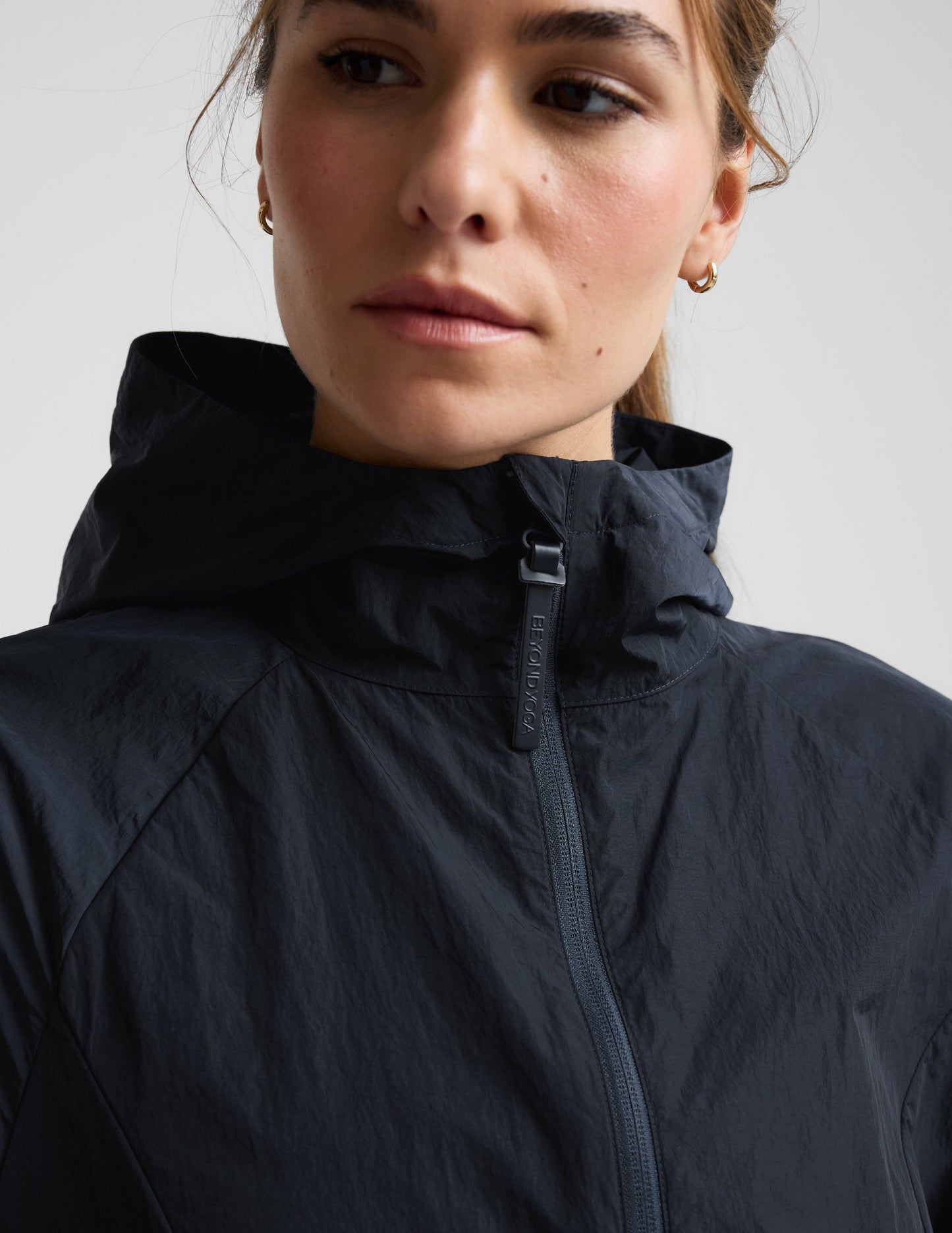 Woman wearing a blue hooded jacket and shorts against a plain background.