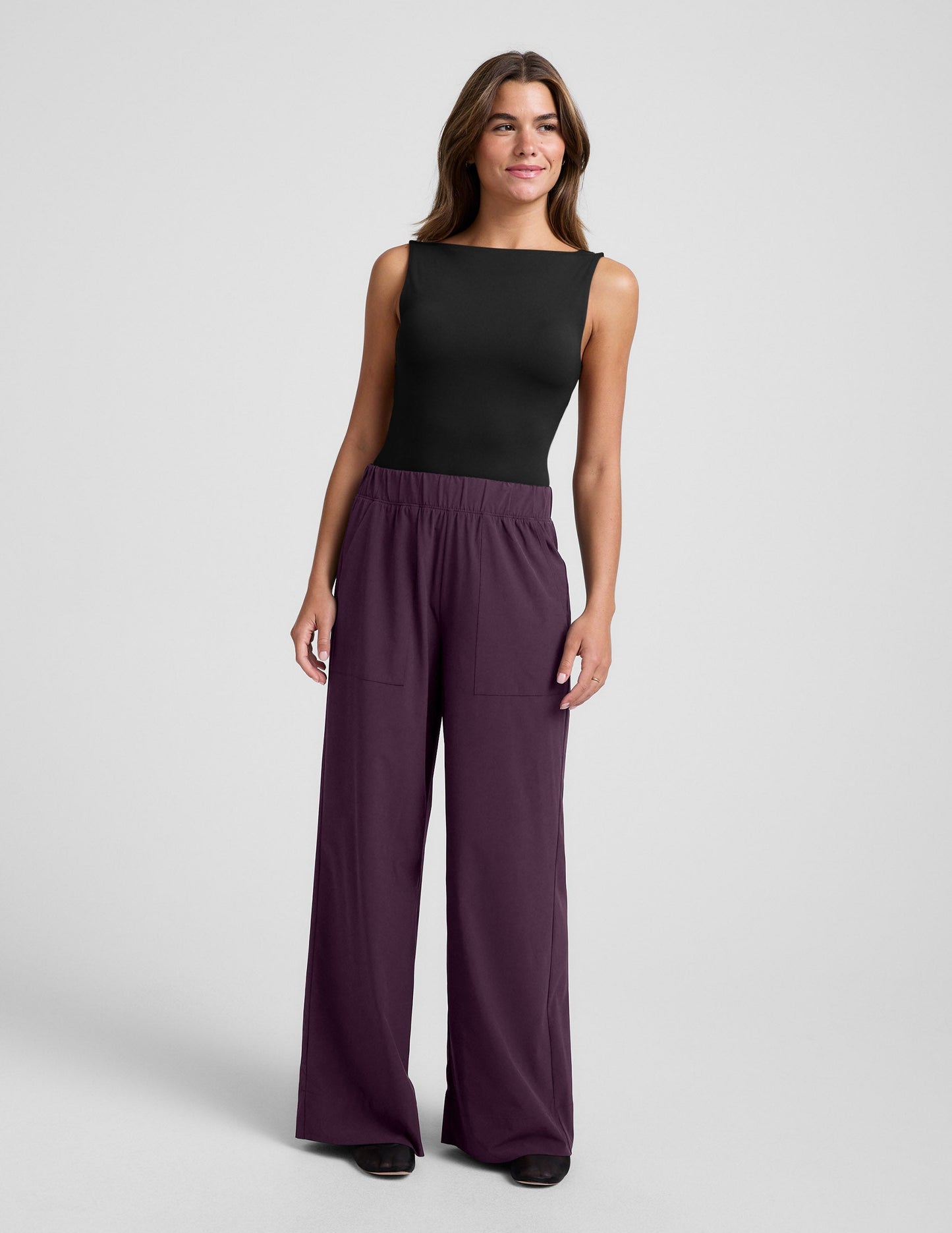 Woman wearing Plum Easy Wide Leg Pant 29" with a black sleeveless top, featuring a gathered elastic waistband and pockets.