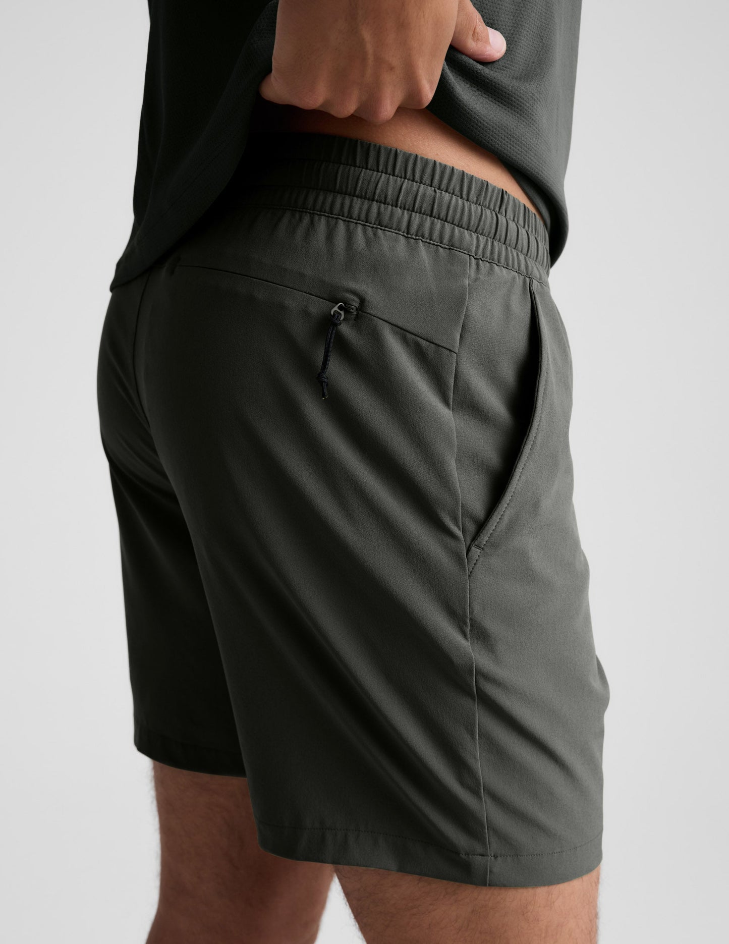 Rear view of man wearing Olive Pivotal 2.0™ Men's Short 7" with a grey shirt, featuring a back yoke invisible zip pocket.