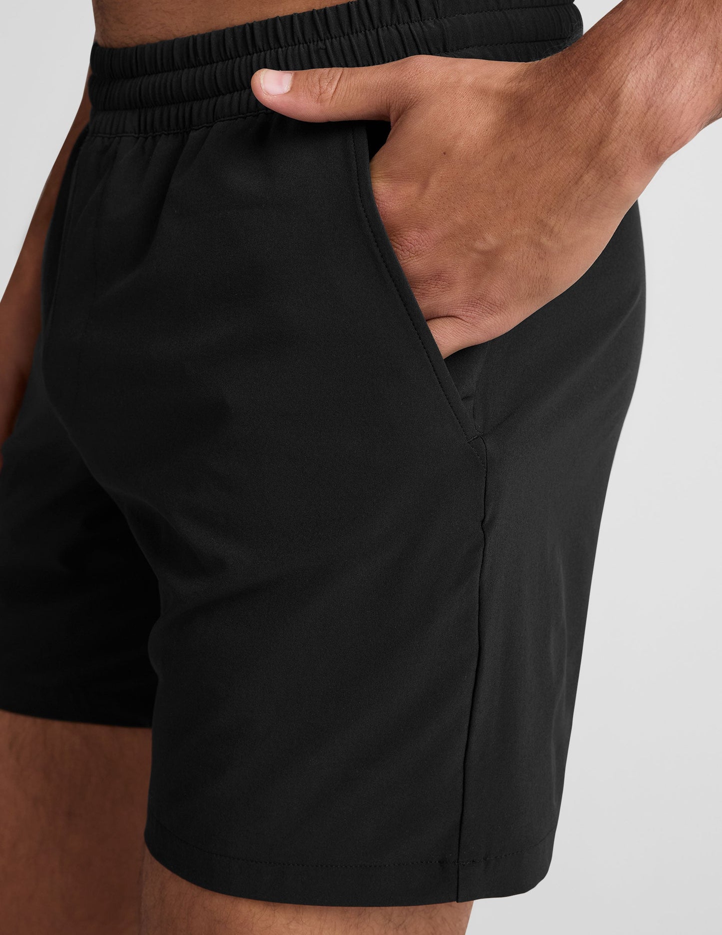Side view of black Pivotal 2.0 Men's Short 7" showing the elastic waistband and a hand resting in the side pocket.
