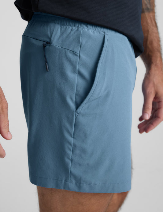 Side view of blue Pivotal 2.0 Men's Lined Short 5" showing side pocket, back zipper pocket, and elastic waistband.