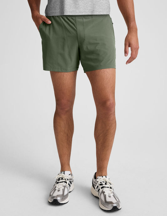 Front view of a man wearing olive Pivotal 2.0 Men's Lined Short 5" with elastic waistband and side pockets.