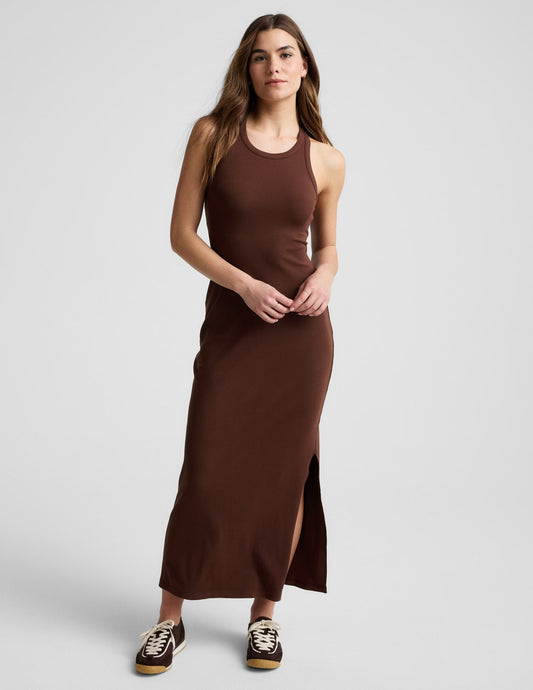 Woman wearing a ribbed brown maxi dress against a plain background.