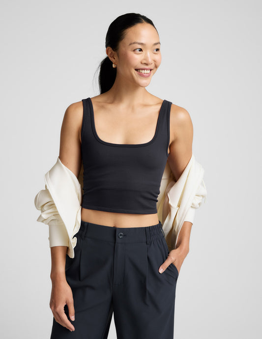 Woman wearing a blue ribbed cropped tank and blue pants against a plain background.