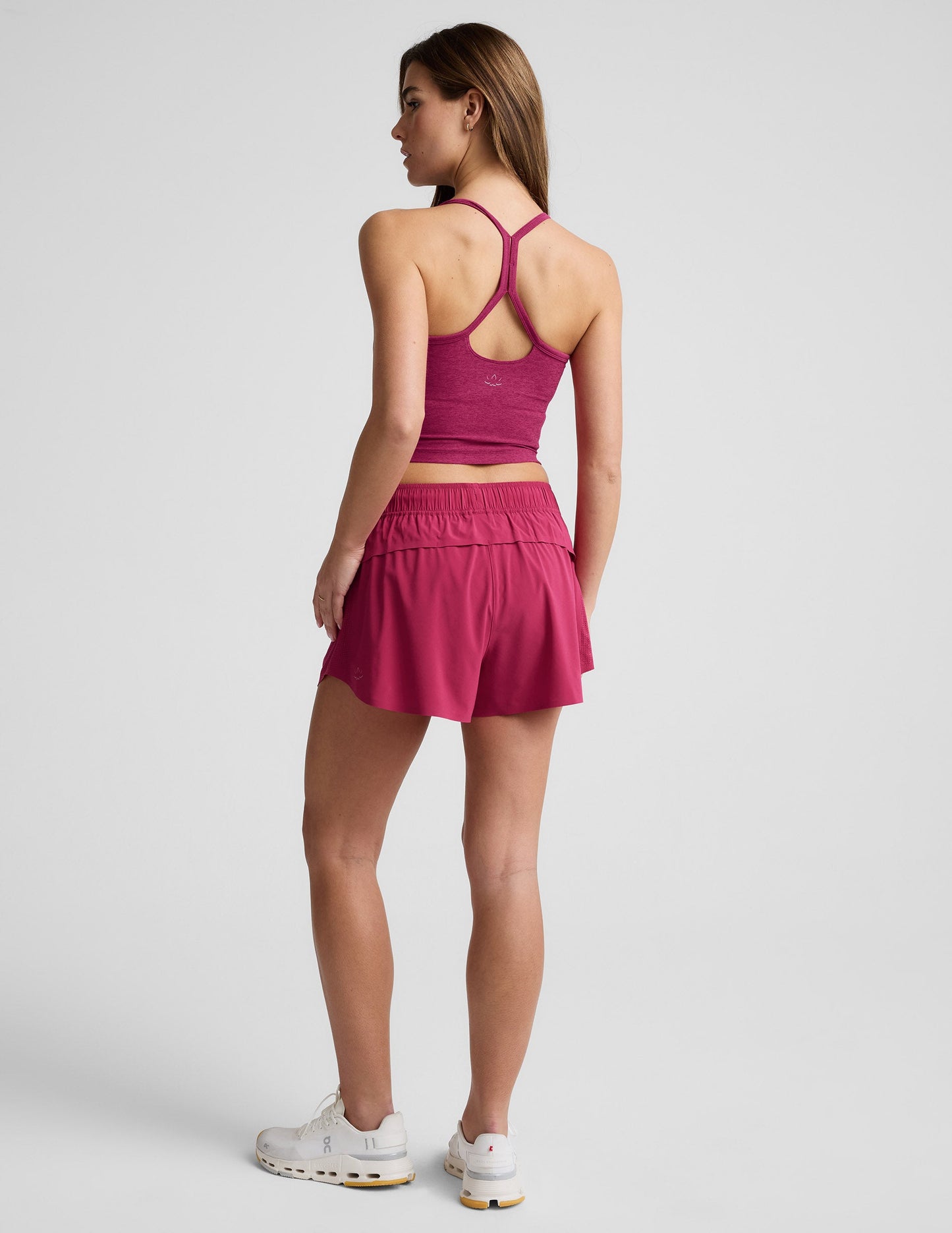 Back view of a woman wearing fuchsia Solemate 2.5" Shorts with a smocked waistband and matching tank top.
