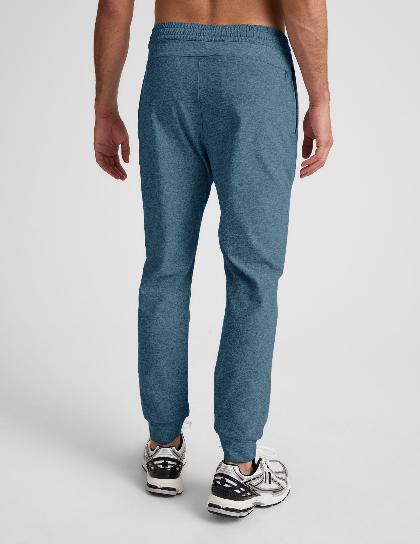Rear view of man wearing Blue Spacedye Freefit Men's Jogger with banded cuffs, paired with white and black sneakers.