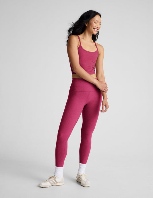 Woman wearing a red cropped tank and leggings against a plain background.