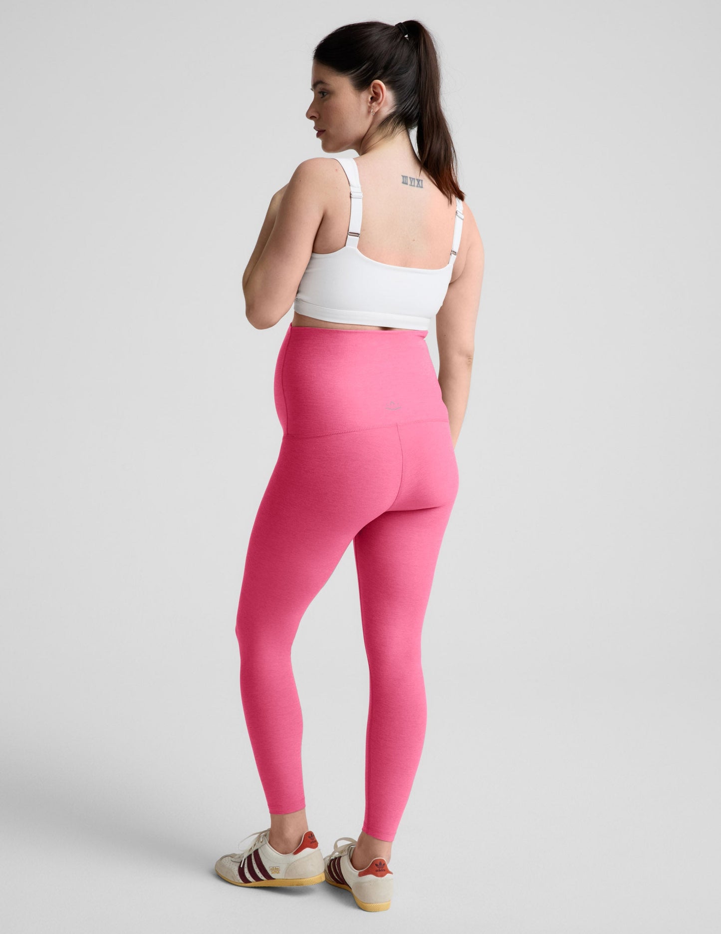 Woman wearing a white maternity bra and leggings against a plain background.