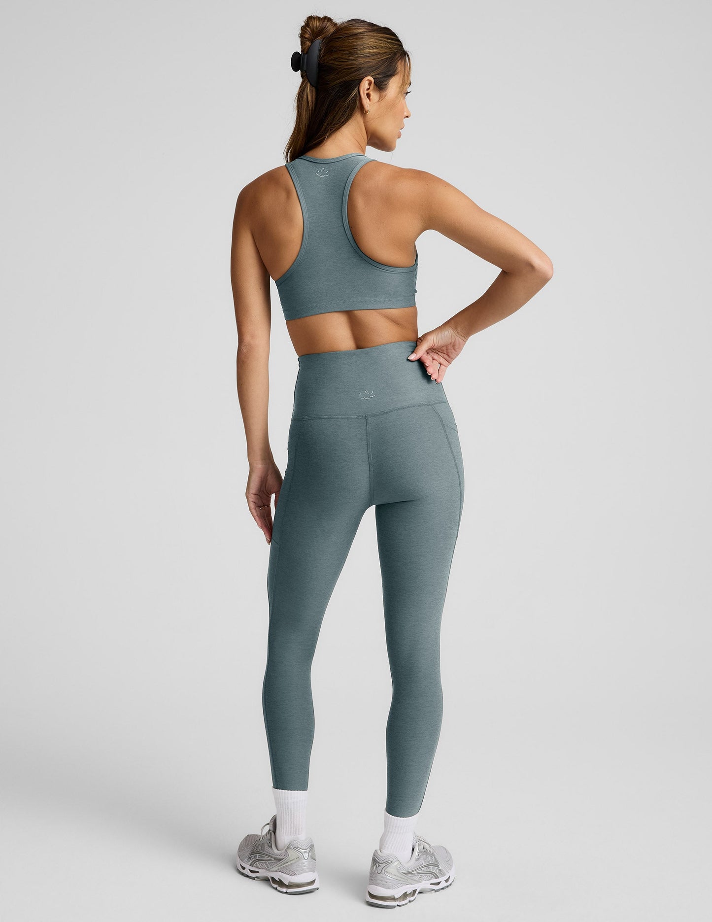 Woman wearing a gray bra and leggings against a plain background.