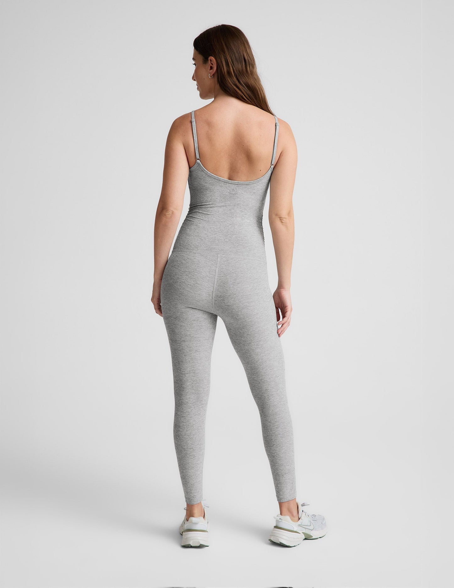 Woman wearing a gray maternity jumpsuit on a white background.