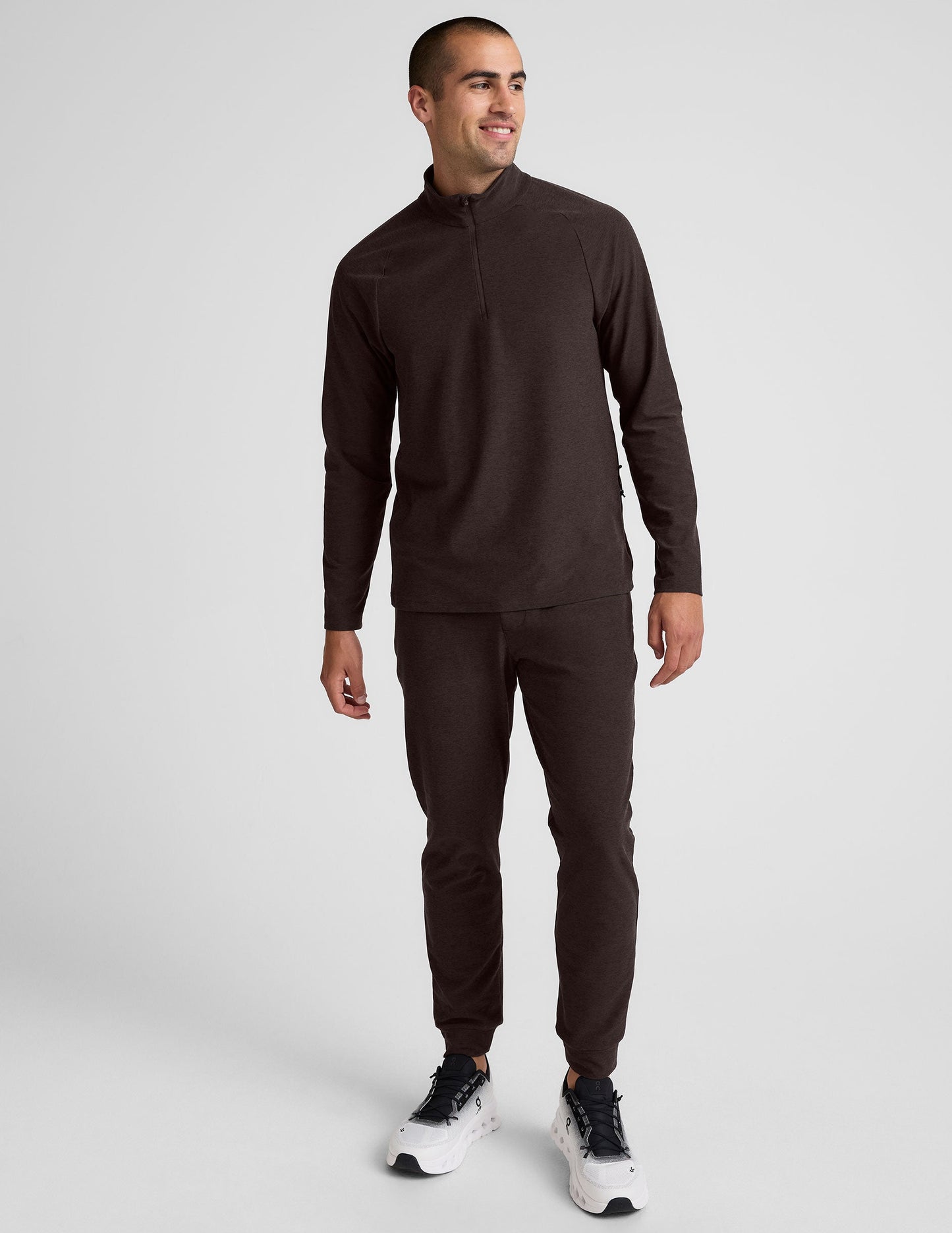 model wearing a brown men's quarter-zip pullover against a plain background.