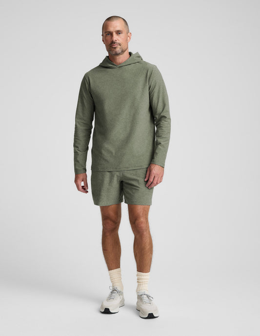 Man wearing a green hoodie and shorts set on a white background.
