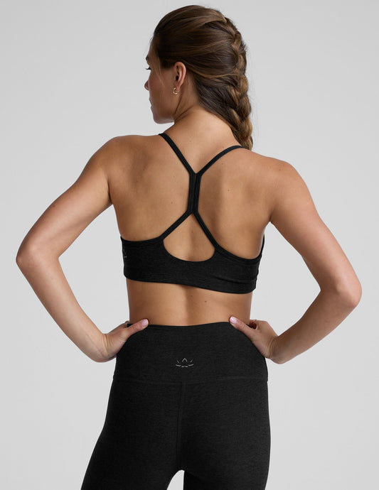 woman wearing a black slim racerback bra and leggings on a plain background.