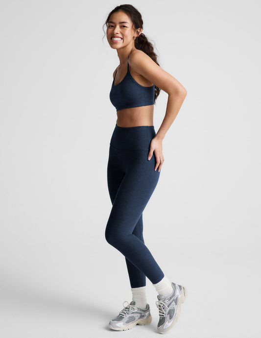 Woman wearing a blue bra and leggings against a plain background.