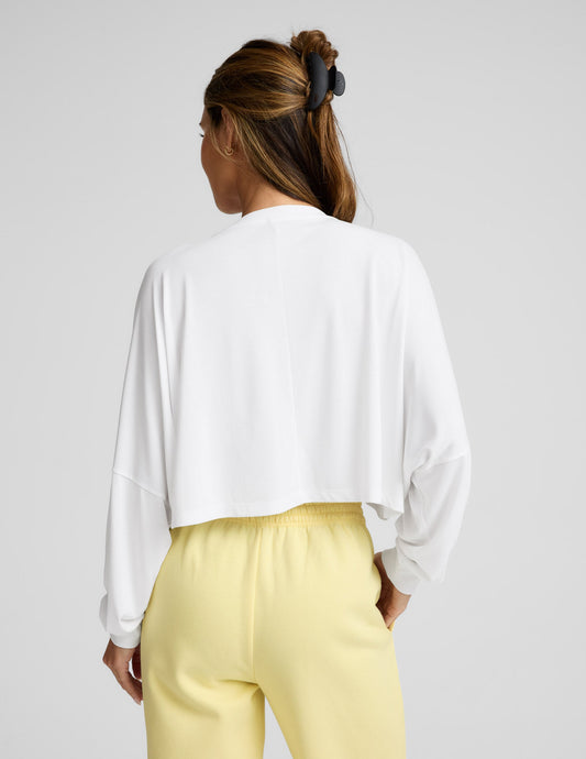 Person wearing a white long sleeve top and yellow pants on a plain background.