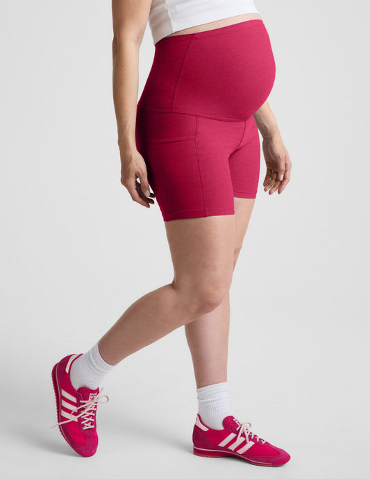 Woman wearing Pink Spacedye™ Keep Pace 5" Maternity Pocket Biker Short paired with a white tank top and sneakers.